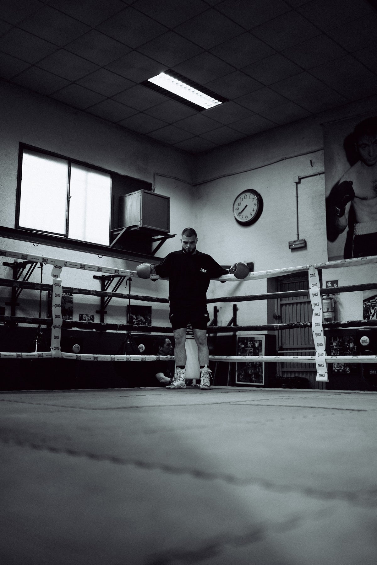 Boxer alone in an empty ring, leaning on the ropes with his head down
