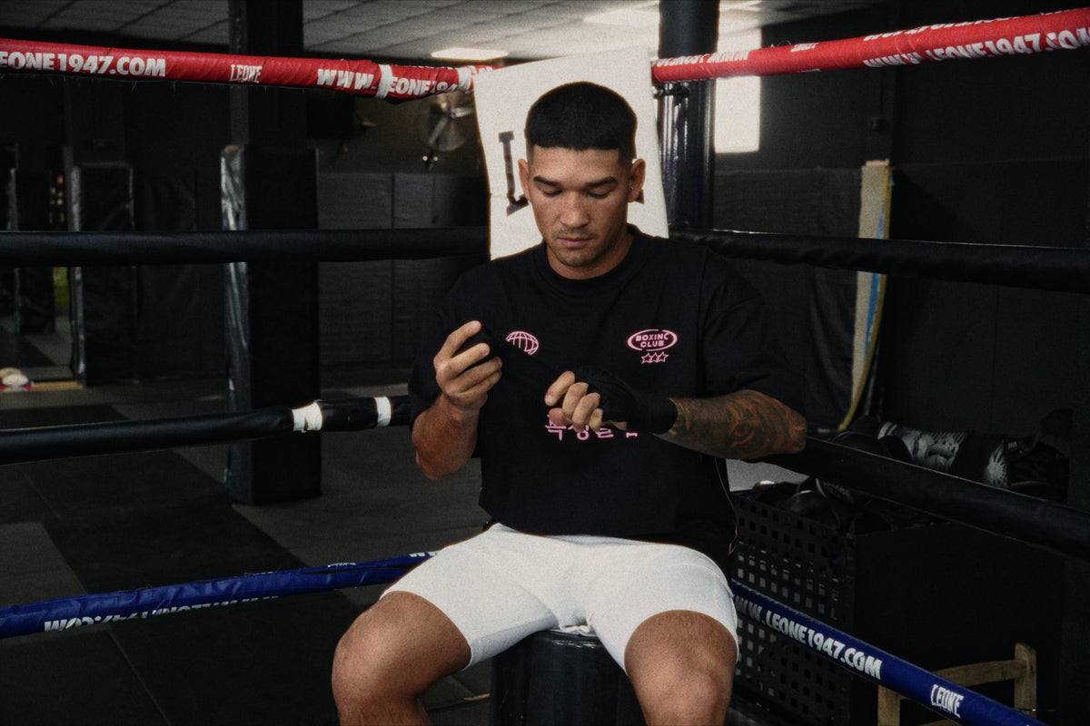 Boxer in the black International Boxing Club tee wrapping his hands in the ring
